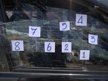 Eight bullet entry points mark the driver's side window of the pickup