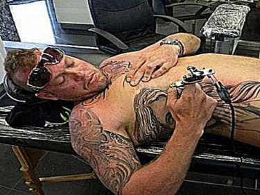 Kenny Bakker administers his own tattoo