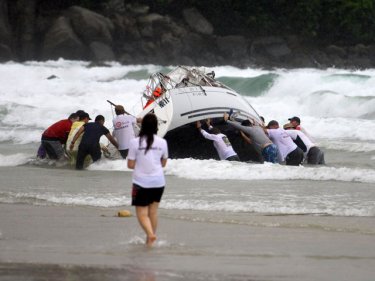 Phuket crew try to right one of at least 10 yachts beached in a storm
