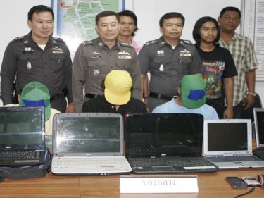 If the cap fits: Senior police, including Phuket Police Commander Major General Pekad Tantipong (centre) with the three laptop thieves