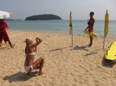 A tourist snaps her friend posing as a Phuket lifeguard at Hai Harn