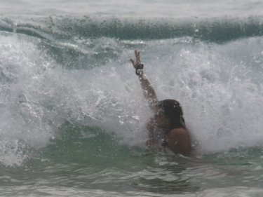 A woman plays in the Karon surf where others have drowned