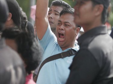 A Phuket demonstrator vents his anger behind police protest lines