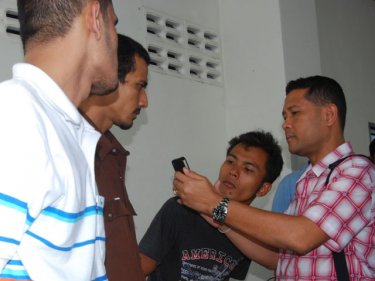 Three handcuffed men being interviewed at Tachatchai on Phuket yesterday