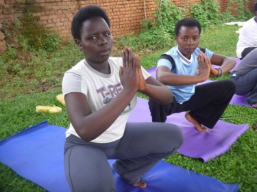 Two young women practice yoga under the project in Rwanda