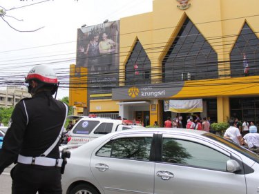 A crowd gathers outside the Phuket City bank where the pair were killed