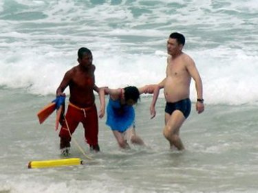 A Chinese woman is helped from the water at Kata beach yesterday