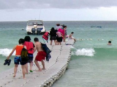 Tourists ride a monsoon pontoon pier at popular Racha, off Phuket