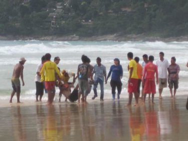 A young man is pulled from the water at Karon beach yesterday