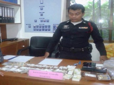 A Phuket police officer inspects the haul from the ATM skimmer suspects