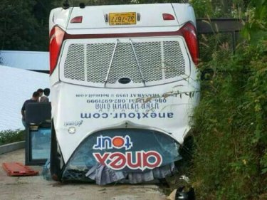 The anex tour bus on its roof after crashing off Phuket's Patong-Kamala road