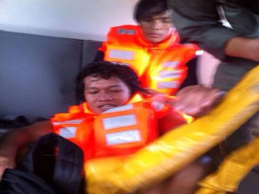 Two crew being rescued from a wrecked cargo ship on rocks off Phuket