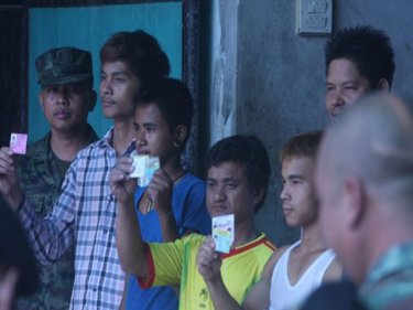 Migrant workers show their cards during a raid in Ranong earlier this year