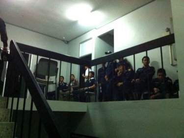 Police inside the Thalang station await developments with a mob outside