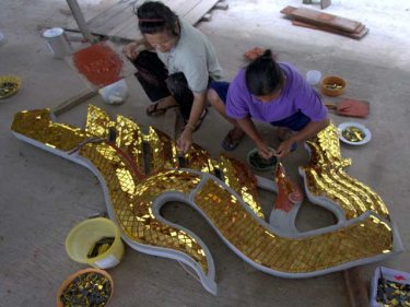 Workers attach small shining pieces to a choafa for the wat