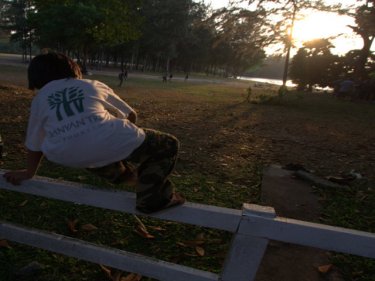 A boy in a Banyan Tree shirt hurdles a fence to play at Laguna Phuket