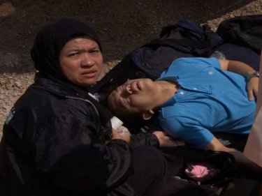 A villager tends an injured tourist after a minibus crash in December
