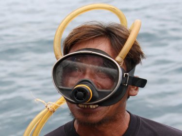 A Phuket sea gypsy diver tests his mask above the water