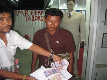 Collector Saichon Chotdee is arrested outside a Phuket tailor shop