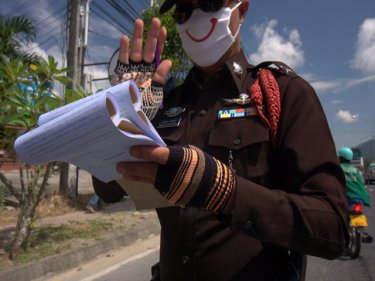 Smiling policeman writes a ticket at a central Phuket checkpoint today