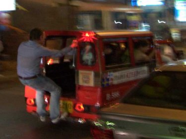 A New Year reveller swings from a tuk-tuk as a woman takes video