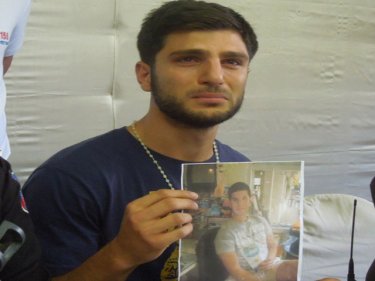 Joseph Tzouvanni holds a photograph of his missing brother, Michael, today