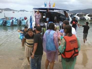 A speedboat drops rescued passengers ashore on Phuket late today