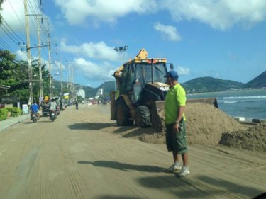 A grader works to push sand from the Kalim road north of Patong yesterday