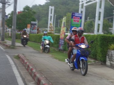 A motorcycle taxi uses a Phuket City footpath to beat gridlocked traffic