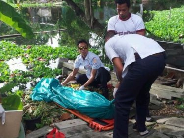 Paramedics recover the man's body from the pond today
