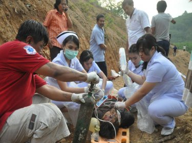 Medics work to help a man who tumbled downhill in an excavator