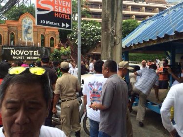 A Phuket crowd gathers today to watch a Patong taxi shack tumble