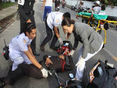 The injured policeman is treated at the Phuket crash scene today