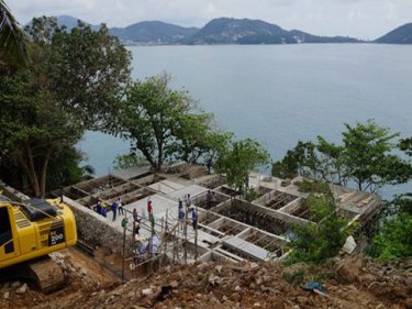 A crane is being used to lower equipment on a steep Phuket site