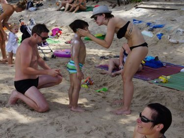 A young tourist gains protection before braving the sunshine on Patong beach