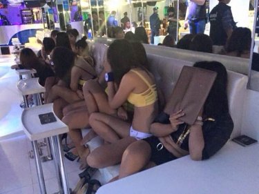 Staff cover up at Pattaya's Skyfall A-Go-Go during a police raid last night