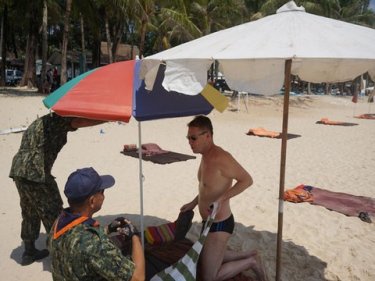 Phuket officials seize beach umbrellas from a tourist at Surin today
