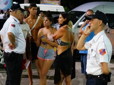 Survivors in swimsuits talk with expat volunteer police on Wednesday night