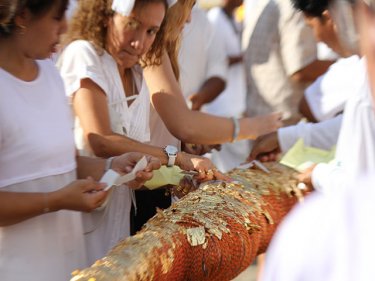 Gold leaf is added to the lantern pole by devotees all dressed in white