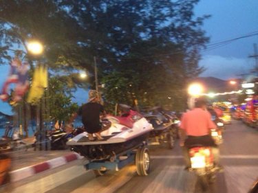 A string of jet-skis being towed by a motorcycle with sidecar in Patong